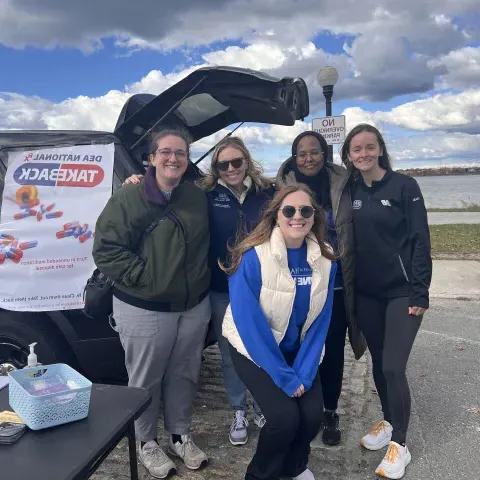 UNE Pharmacy students and faculty pose for a photo by the water at Drug Take Back Day